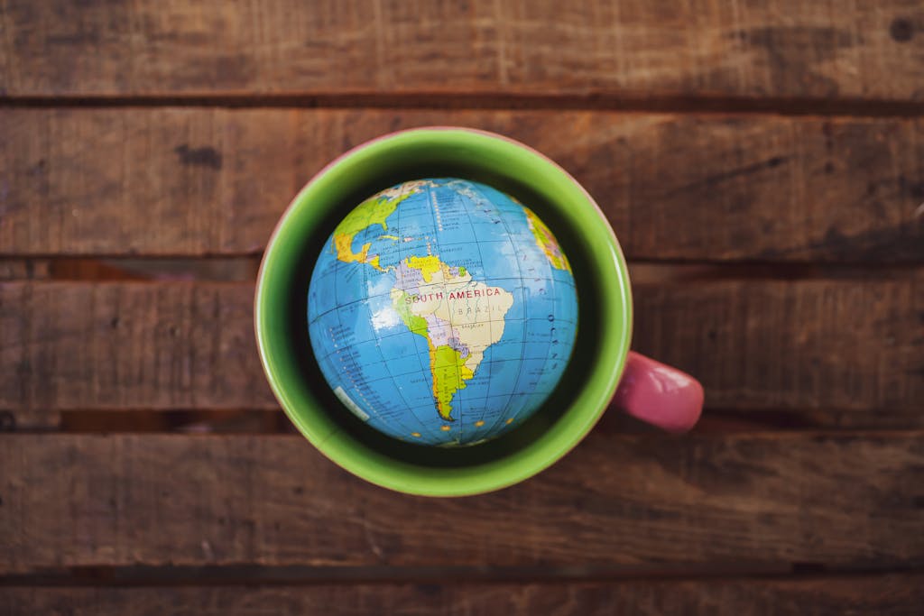 A vibrant globe in a green mug resting on a rustic wooden table.
